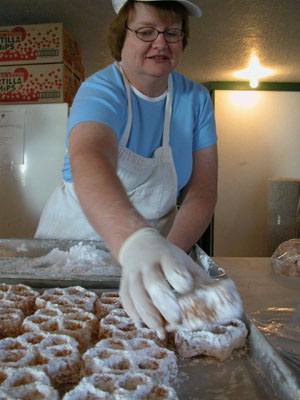Dianna Ireton places another delicious waffle on the tray after rolling it in powdered sugar early this morning in the Knights of Columbus building at the Mercer County Fair. Center photo, other K of C volunteers, Dick Colson (at right) and Carl Deitsch, fry up the sweet creations three at a time.<br> <br>dailystandard.com