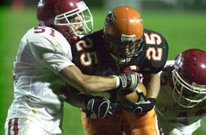 Coldwater's Ross Homan, 25, runs through a pair of St. Henry tackles during a run on Friday night at Cavalier Stadium. Coldwater went on to defeat St. Henry, 31-7.<br></br>dailystandard.com